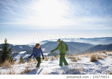 Active seniors having snowball fight. Romantic winter hike for an elderly couple in snowy mountains. 120779913