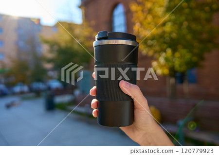 Woman holding reusable coffee cup on blurred autumn background. Concept of sustainable and eco-friendly living Woman holding reusable coffee cup on blurred autumn background. Concept of sustainable and eco-friendly living 120779923