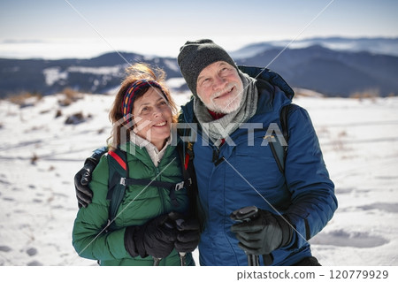 Portrait of active seniors enjoying nature. Romantic winter hike for an elderly couple in snowy mountains. 120779929