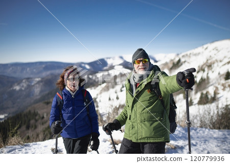 Romantic winter hike for an elderly couple in snowy mountains. Active seniors enjoying nature. 120779936