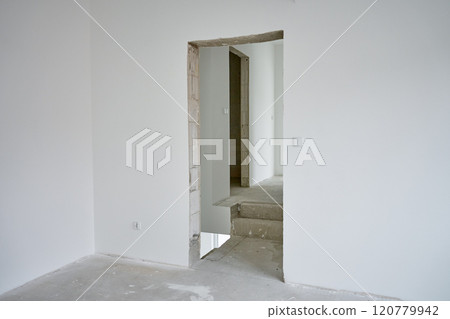 Empty apartment with white walls and concrete floor undergoing renovation. Interior of building under construction 120779942