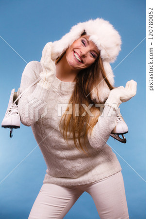 Woman wearing winter hat holding ice skate 120780052