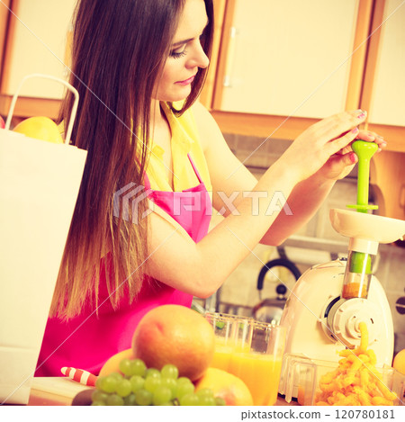 Woman making orange juice in juicer machine 120780181