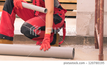 Woman carrying pipes on construction site 120780195