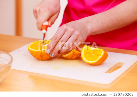Woman housewife in kitchen cutting orange fruits 120780202