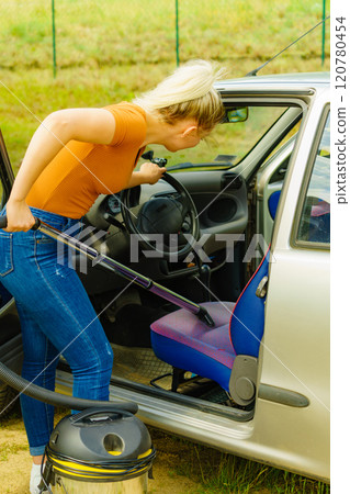 Cleaning car interior with vacuum cleaner 120780454