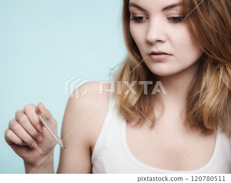 Flu. Sick girl with fever checking thermometer. 120780511