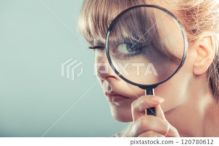 Woman hand holding magnifying glass on eye 120780612