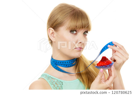 Woman holds cupcake trying to resist temptation 120780625