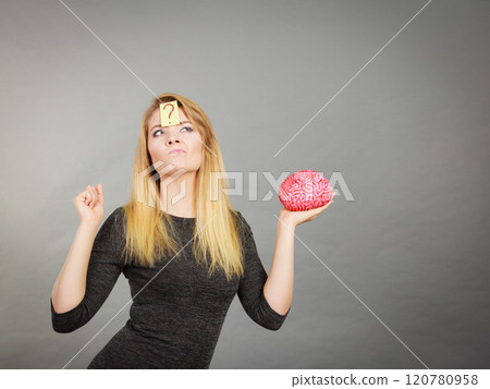 Woman thinking and holding fake brain Woman thinking and holding fake brain 120780958