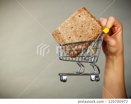 Woman hand holding shopping cart with bread Woman hand holding shopping cart with bread 120780972