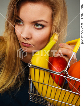 Woman holding shopping basket with fruits inside 120780982