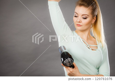Woman drying armpit with hair dryer Woman drying armpit with hair dryer 120781076