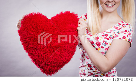 Happy woman holding heart shaped pillow Happy woman holding heart shaped pillow 120781078