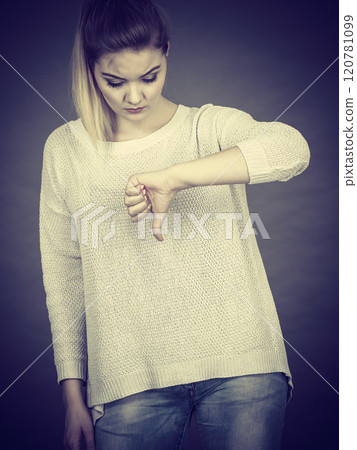 Sad woman showing thumb down gesture 120781099