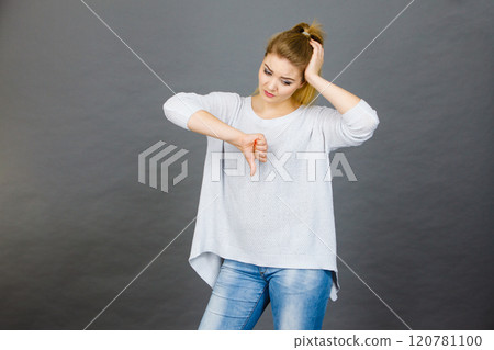 Sad woman showing thumb down gesture 120781100