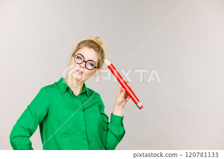 Woman confused thinking, big pencil in hand Woman confused thinking, big pencil in hand 120781133