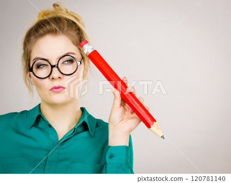 Woman confused thinking, big pencil in hand 120781140