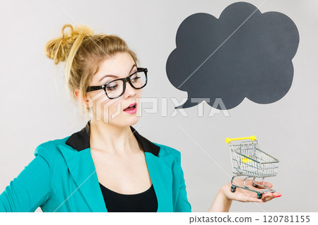 Thinking business woman holding small tiny shopping cart Thinking business woman holding small tiny shopping cart 120781155