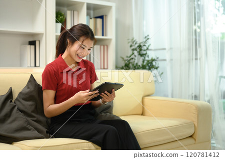 Attractive young asian woman using digital tablet on sofa at home 120781412