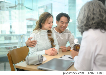 Cheerful young couple listening attentively while senior doctor explaining treatment during consultation 120781489
