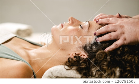 Beautician massaging woman's forehead in beauty center Beautician massaging woman's forehead in beauty center 120781503