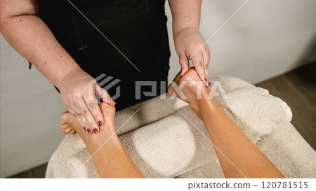 Masseuse giving relaxing foot massage to client in spa Masseuse giving relaxing foot massage to client in spa 120781515