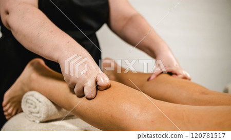 Masseuse giving leg massage to client in spa 120781517