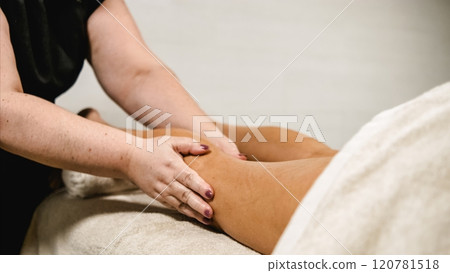 Masseuse giving leg massage to client in spa 120781518