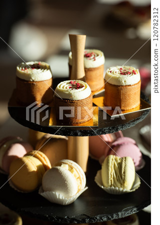 A table with a variety of desserts and pastries. The desserts are arranged in glass bowls and trays 120782312