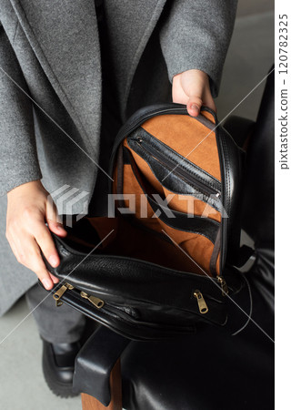 woman holds a black leather backpack. open, empty bag woman holds a black leather backpack. open, empty bag 120782325