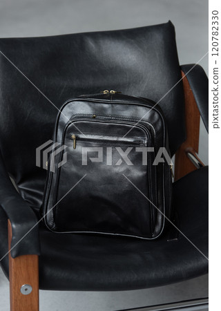 Black leather backpack on the stylish chair 120782330