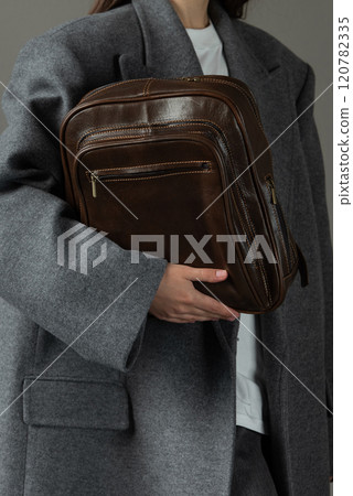 woman posing with a leather backpack wearing a warm gray coat woman posing with a leather backpack wearing a warm gray coat 120782335