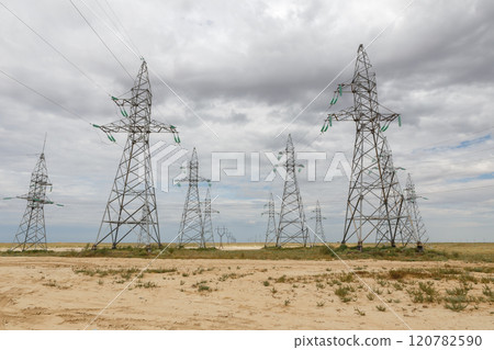 Power lines stretch across an open landscape under a cloudy sky in a rural area 120782590