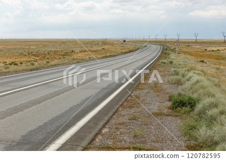 Expansive highway stretching through the serene landscape of Kazakhstan's steppe region Expansive highway stretching through the serene landscape of Kazakhstan's steppe region 120782595