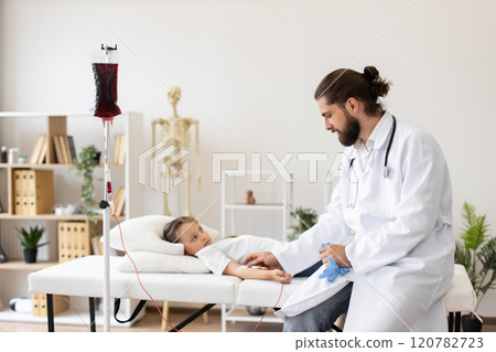 Male doctor assists young Caucasian girl receiving blood transfusion at medical facility. Scene captures essence of care and empathy in healthcare setting, highlighting doctor-patient professionalism. 120782723