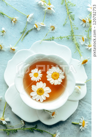 Chamomile flower tea. A tea cup with infusing blossoms, overhead flat lay shot 120782753