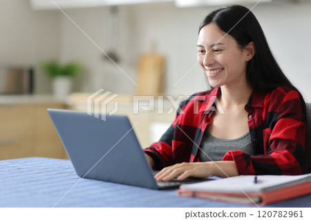 Happy asian student e-learning checking laptop in the kitchen 120782961