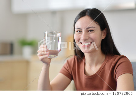 Happy asian woman holding water glass in the kitchen Happy asian woman holding water glass in the kitchen 120782965