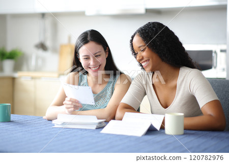Happy interracial roommates or lesbian couple checking invoice 120782976
