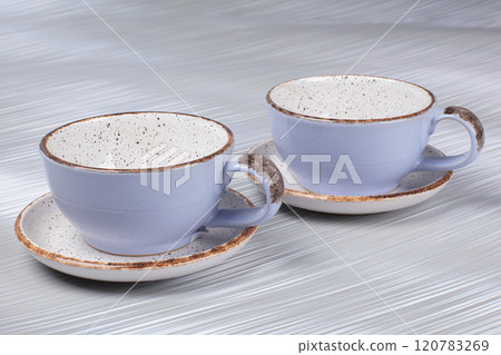 Ceramic clay cups and saucers on a gray background. 120783269