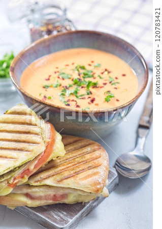 Red bell pepper cream soup served with grilled turkey panini, vertical 120783421