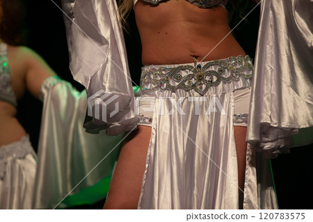 An unrecognizable woman in white clothes is dancing a belly dance. 120783575