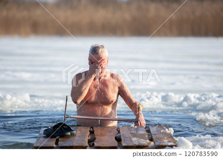 An elderly man bathes in an ice hole on the Orthodox feast of the Epiphany. Take a dip in the icy water. 120783590
