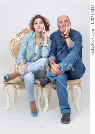 A funny portrait of an adult daughter and an elderly father in denim clothes on a gray background. 120783822