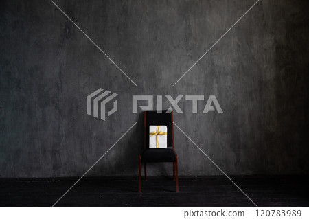 Chair with holiday gift in the interior of a dark living room Chair with holiday gift in the interior of a dark living room 120783989