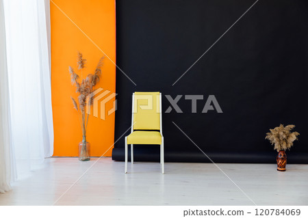 Yellow chair and dried flowers in the interior of a black and orange room Yellow chair and dried flowers in the interior of a black and orange room 120784069