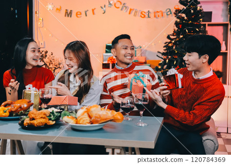 Friends opening Christmas gifts in living room 120784369