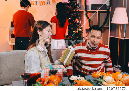 Friends opening Christmas gifts in living room Friends opening Christmas gifts in living room 120784372