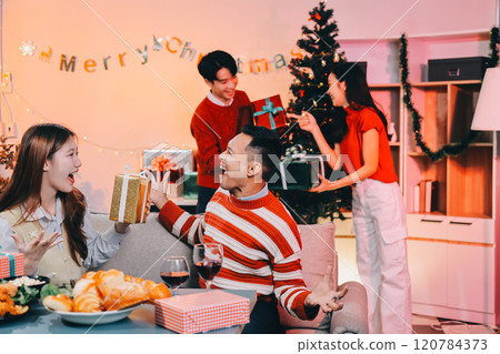 Friends opening Christmas gifts in living room Friends opening Christmas gifts in living room 120784373